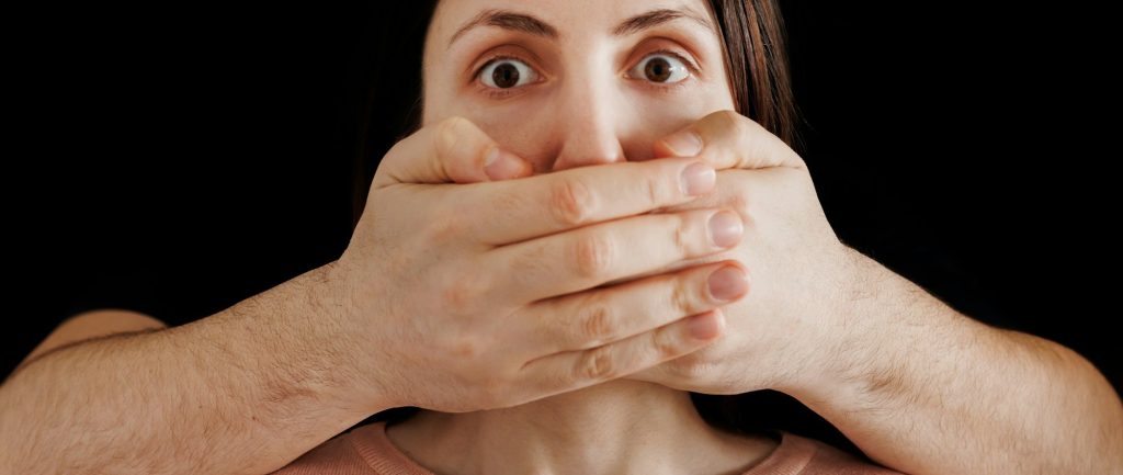 Man hand closes woman mouth, russian flag in the background. censorship concept